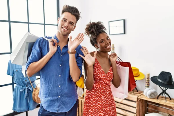 在零售店拿着购物袋的两对跨种族年轻夫妇一边说 一边笑着 友好地欢迎 — 图库照片