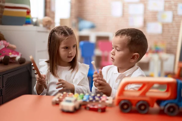 愛らしい女の子と男の子遊びますXylophone座っている上のテーブルの上に幼稚園 — ストック写真