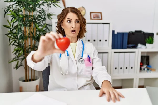 Médico Mediana Edad Mujer Sosteniendo Corazón Clínica Abrazándose Feliz Positivo —  Fotos de Stock