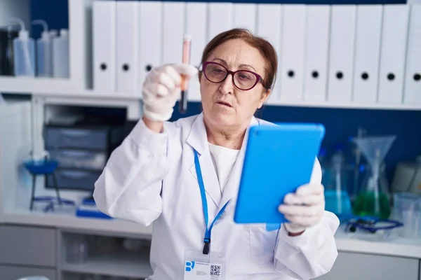 Ανώτερη Γυναίκα Επιστήμονας Χρησιμοποιώντας Touchpad Κρατώντας Σωλήνα Εξέταση Αίματος Στο — Φωτογραφία Αρχείου