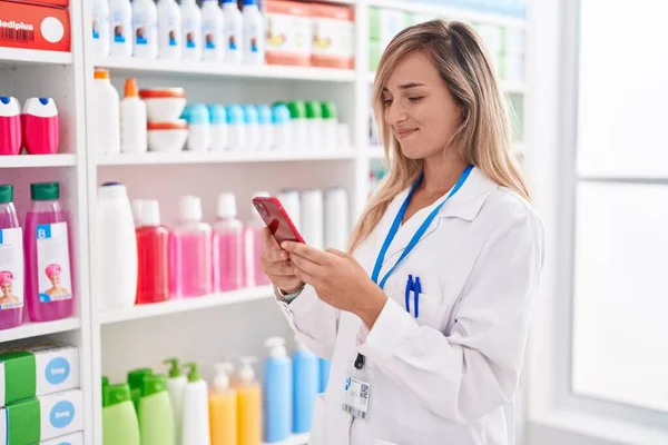 Young Blonde Woman Pharmacist Using Smartphone Working Pharmacy — Stok fotoğraf