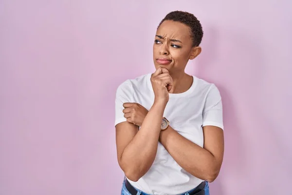 Beautiful african american woman standing over pink background thinking worried about a question, concerned and nervous with hand on chin
