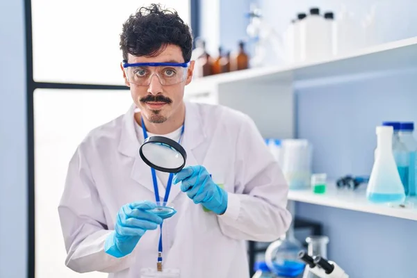 Genç Beyaz Bilim Adamı Laboratuvarda Büyüteç Kullanarak Gülümsüyor — Stok fotoğraf