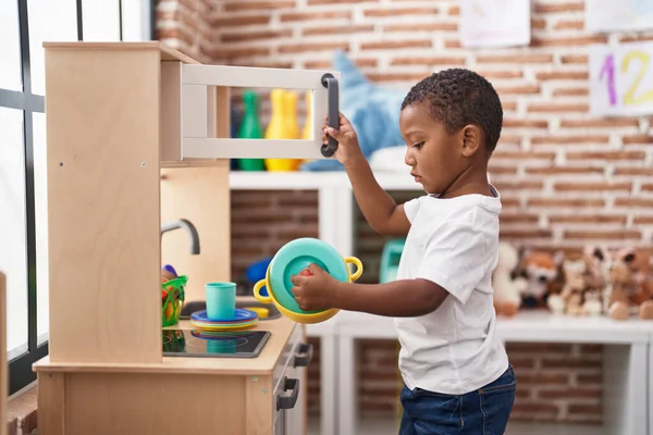 非裔美国男孩站在幼儿园的游戏厨房里玩耍 — 图库照片