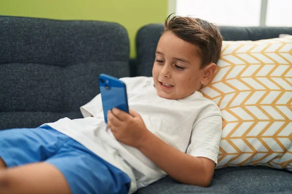 Adorable Niño Hispano Usando Teléfono Inteligente Tumbado Sofá Casa —  Fotos de Stock