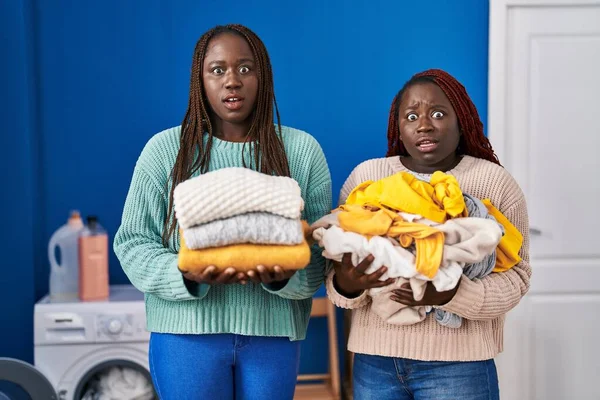 Две Африканские Женщины Держащие Сложенное Белье После Глажки Шокирующем Лице — стоковое фото