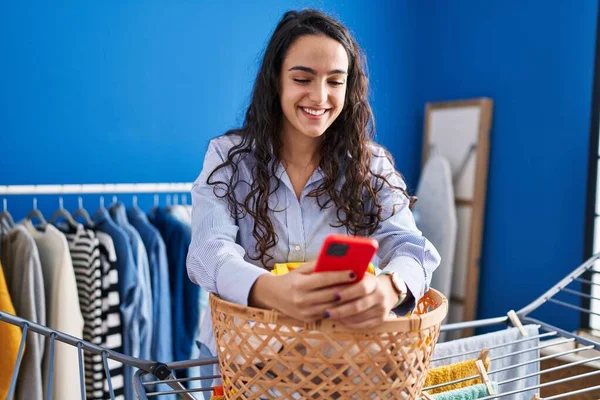 Young Hispanic Woman Using Smartphone Standing Laundry Room — Foto de Stock