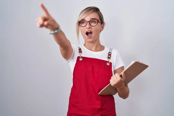 Young Blonde Woman Wearing Waiter Uniform Holding Clipboard Pointing Finger — Stock Photo, Image