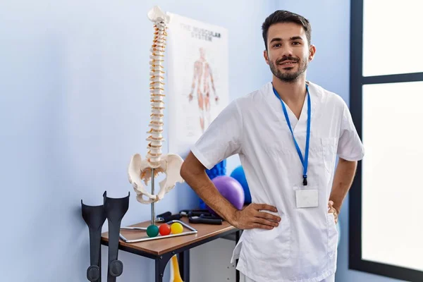 Young Hispanic Man Wearing Physiotherapist Uniform Standing Rehab Clinic — Stockfoto