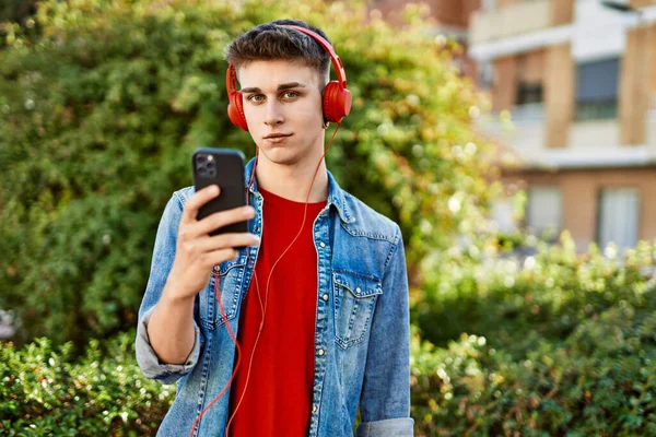 市内で音楽を聴くヘッドフォンを身に着けている若い白人男性 — ストック写真