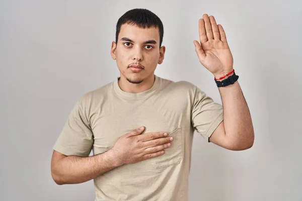 胸と手のひらに手で身に着けているカジュアルなTシャツを身に着けている若いアラブ人男性 忠誠の誓いを作る — ストック写真
