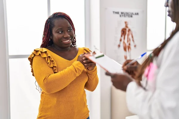 アフリカ系アメリカ人の女性医師や患者が診療所で診察を受け — ストック写真