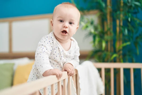 可爱的高加索婴儿站在卧房的摇篮上 — 图库照片