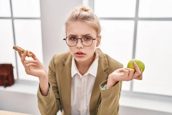 Young Caucasian Woman Working Office Eating Snack Clueless Confused Expression — Stockfoto