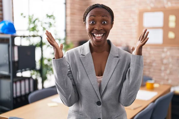 アフリカ系アメリカ人女性がオフィスで笑顔で勝利を祝い 手を上げて勝者の表情で — ストック写真