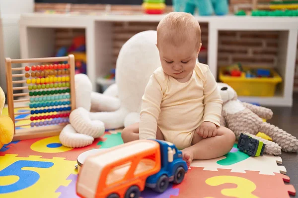 可爱的高加索婴儿在幼儿园的地板上玩汽车和卡车玩具 — 图库照片