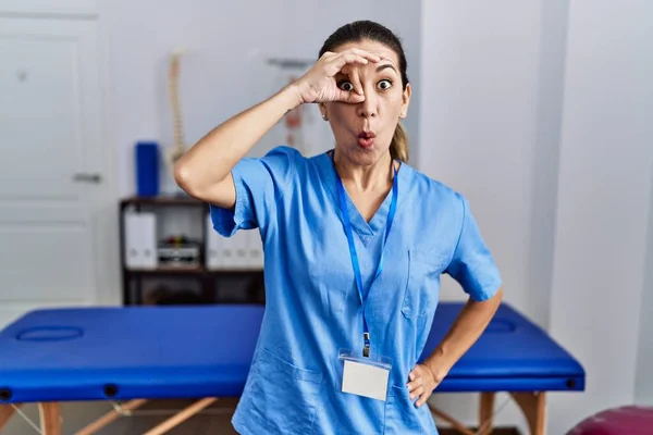 Mladá Hispánka Uniformě Fyzioterapeutky Stojící Klinice Dělá Pořádku Gesto Šokované — Stock fotografie