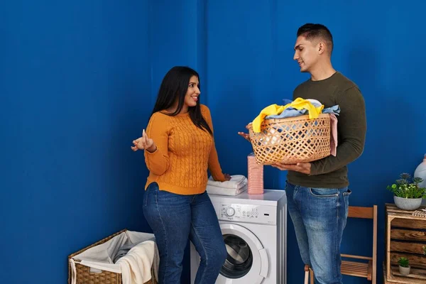 男性と女性のカップルは洗濯室で話す服とバスケットを保持 — ストック写真