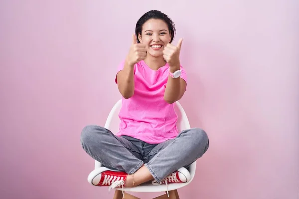 Hispanic Young Woman Sitting Chair Pink Background Success Sign Doing — 图库照片