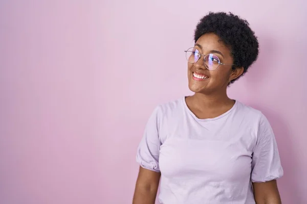 年轻的非洲裔美国女人站在粉红的背景上 面带微笑 自然地看着旁边 充满自信地大笑 — 图库照片