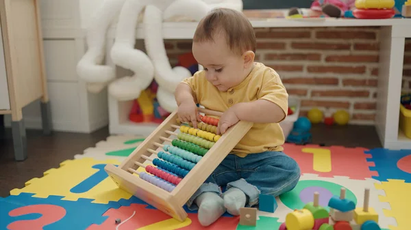 stock image Adorable hispanic baby playing with abacus sitting on floor at kindergarten