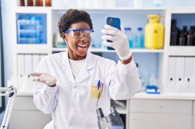 Afrika kökenli Amerikalı bir kadın bilim adamının laboratuarında çalışıyor. Akıllı telefonuyla başarıyı mutlu bir gülümsemeyle kutluyor ve kazanan ifade elini kaldırıyor. 