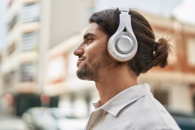 Sokakta müzik dinlerken kendinden emin gülümseyen İspanyol genç adam.