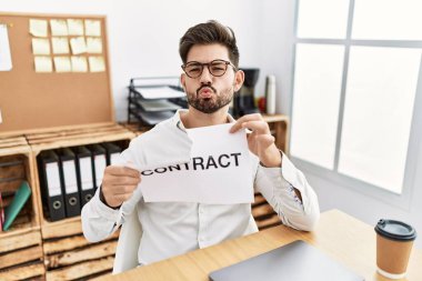 Young man with beard breaking contract paper at the office looking at the camera blowing a kiss being lovely and sexy. love expression. 