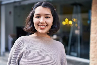 Young woman smiling confident looking to the camera at street