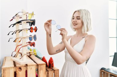 Giysi mağazasında kendine güvenen, gülümseyen beyaz bir kadın.