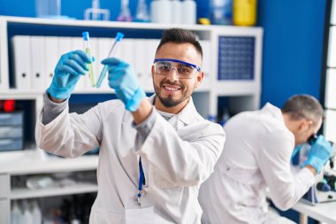 Two men scientists holding test tubes using microscope at laboratory
