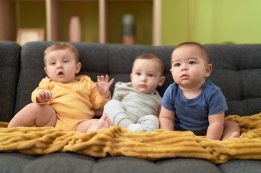 Evdeki kanepede oturan bir grup çocuk.