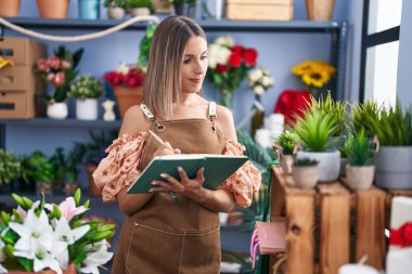 Çiçekçide deftere yazan güzel İspanyol bir çiçekçi kadın.