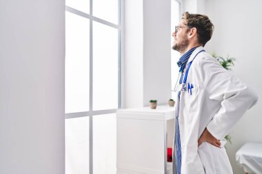 Young man doctor looking throw the window standing at clinic