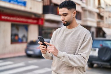 Sokakta akıllı telefon kullanan genç bir Arap.