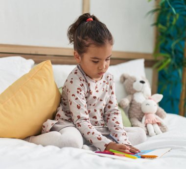 Yatak odasına oturmuş defterine resim çizen sevimli İspanyol kız.