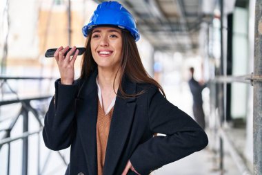 Genç, güzel, İspanyol bir mimar gülümsüyor. Akıllı telefondan kendine güvenen bir sesli mesaj dinliyor.