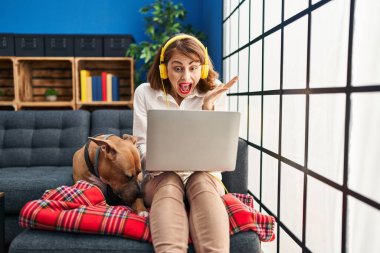 Dizüstü bilgisayar kullanan genç ve güzel bir kadın zaferi mutlu bir gülümsemeyle ve ellerini kaldırarak kutluyor. 