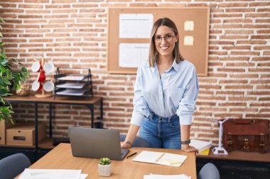 Genç, güzel, İspanyol bir iş kadını. Ofiste kendinden emin bir şekilde gülümsüyor.
