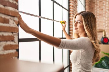 Yeni evindeki kendine güvenen sarışın kadın gülümsüyor.