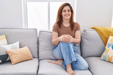 Evdeki koltukta kendinden emin gülümseyen genç bir kadın.