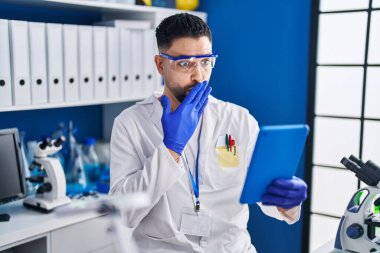 Laboratuvarda çalışan genç yakışıklı bir adam online arama yapıyor. Ağzı eliyle kapatıyor. Şok geçiriyor ve hata yapmaktan korkuyor. şaşırmış ifade 