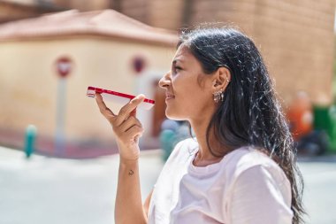 Genç ve güzel İspanyol kadın caddede akıllı telefondan konuşuyor.