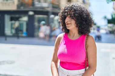 Young middle eastern woman looking to the side with serious expression at street