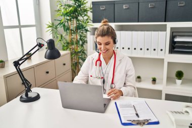 Young doctor woman wearing doctor uniform working using computer laptop looking positive and happy standing and smiling with a confident smile showing teeth 