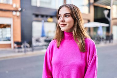 Gülümseyen genç bir kadın sokağın kenarına bakıyor kendinden emin.