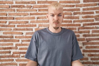 Kafkasyalı genç adam tuğlaların başında duruyor. Duvardan bihaber ve kolları açık, hiçbir fikri yok.. 