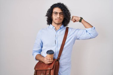 Kıvırcık saçlı İspanyol bir adam bir fincan kahve içerken güçlü biri kol kası gösteriyor, kendinden emin ve gururlu. 