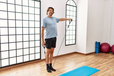 Middle age caucasian man smiling confident training using elastic band at sport center