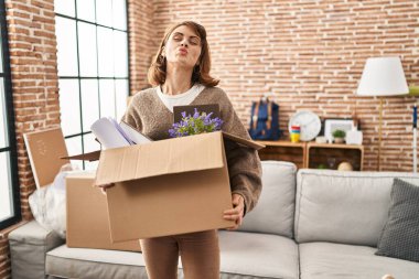 Genç, güzel bir kadın yeni bir eve taşınıyor ve kameraya bakıyor. Öpücük yolluyor, sevimli ve seksi. aşk ifadesi. 